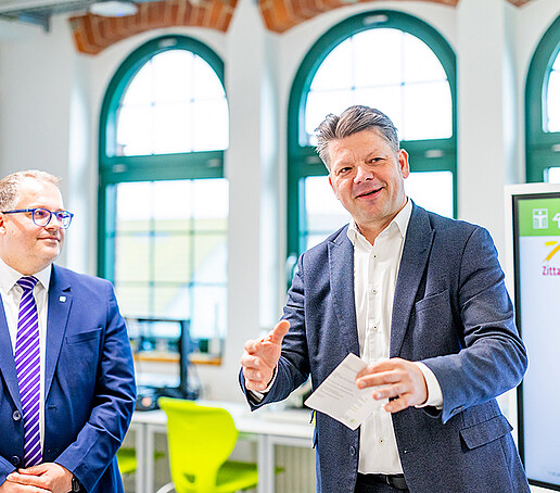 OB Zenker hält einen Zettel in der Hand und hält eine Rede. Daneben steht der Rektor.