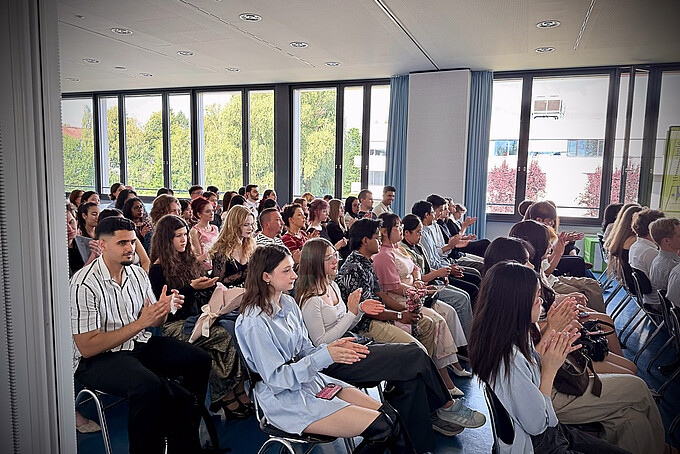 Impressionen der feierlichen Zeugnisübergabe des Studienkollegs der Hochschule Zittau/Görlitz: Absolventinnen und Absolventen verfolgen die Veranstaltung.