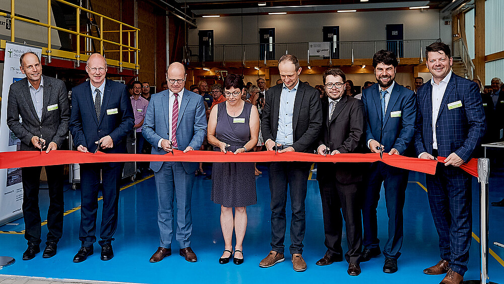 Mehrere Personen zerschneiden ein rotes Band