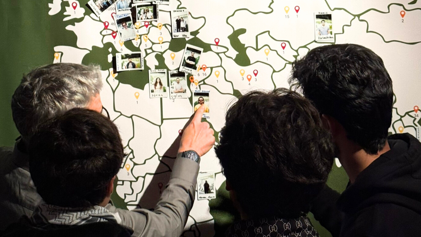 Studierende zeigen mit dem Finger auf eine Weltkarte.