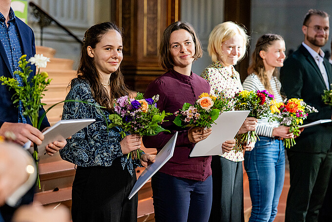 Mehrere Deutschlandstipendiatinnen stehen mit Blumensträußen und Urkunden im Altarraum der Johanniskirche.
