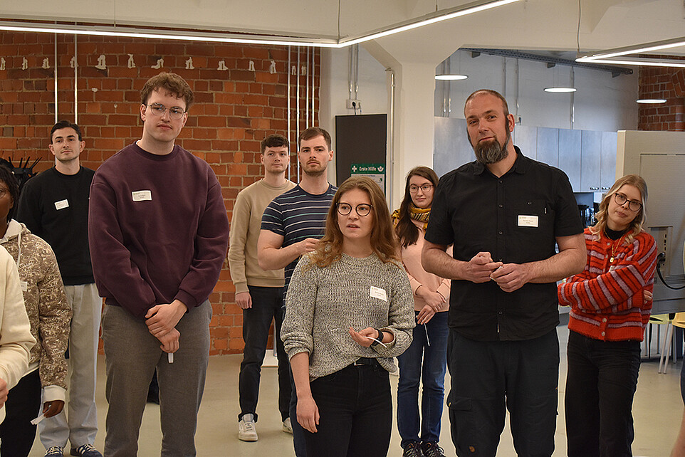 Workshopteilnehmende stehen im Celsiuz-Arbeitsraum nebeneinander und besprechen eine Aufgabe.