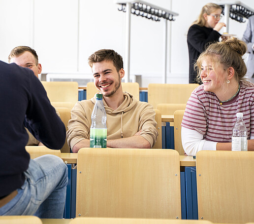 Das Publikum unterhält sich im Vorlesungssaal auf den Sitzreihen.