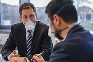 Two men sitting opposite each other wearing mouth and nose mask