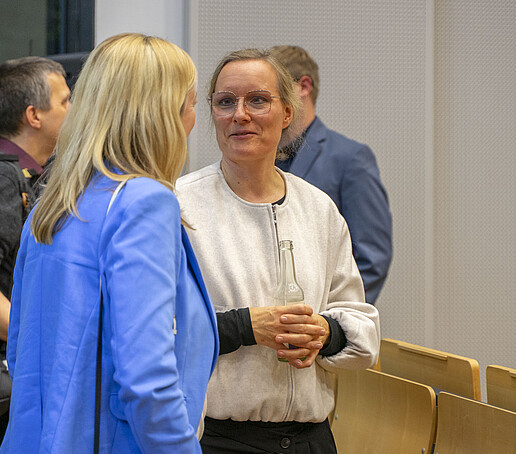 Die Prorektorin unterhält sich mit einer Frau, die eine weiße Jacke trägt.