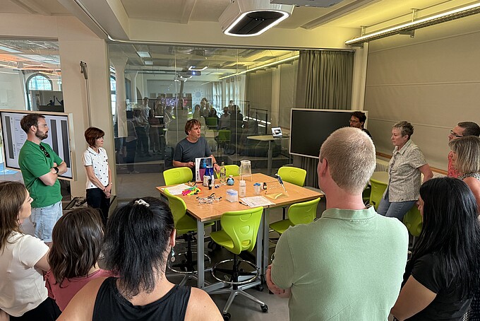 Lehrer und Lehrerinnen stehen im Schülerlabor vor Versuchsständen.