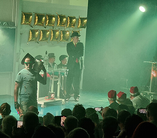 Darsteller auf der Bühne stehen im grünen Licht.