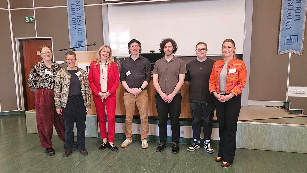 Prorektorin Keil, Inna Hauf und Teilnehmende der ACC-Konferenz stehen zum Gruppenbild nebeneinander vor einer Bühne.