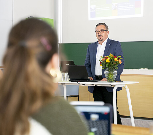 Ein Professor hält eine Rede am Rednerpult im Vorlesungssaal.